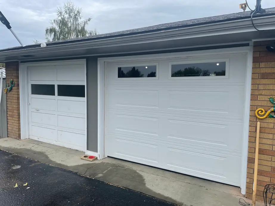 New white garage doors with window tops on a brick house