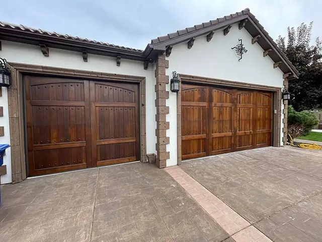 Custom dark-stained wood carriage garage doors on a white stucco house