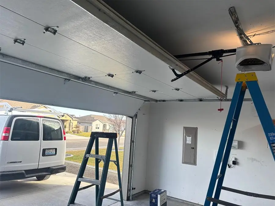 Opener being installed from inside a garage with the company van visible through the open door