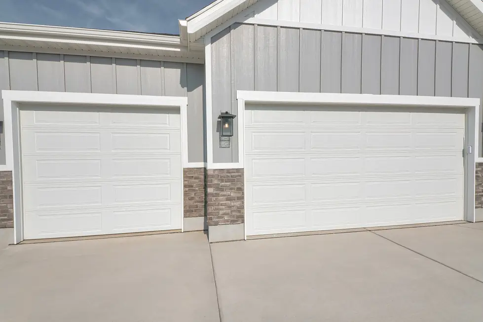 Two white long-panel garage doors on a grey board-and-batten new build